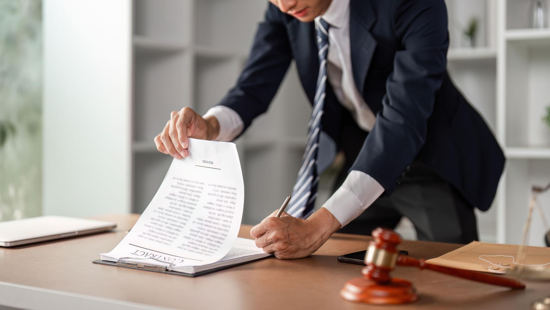 Young Black lawyer reviewing and signing legal contract documents at office desk, focusing on law practice within the Inland Empire area of Southern California..